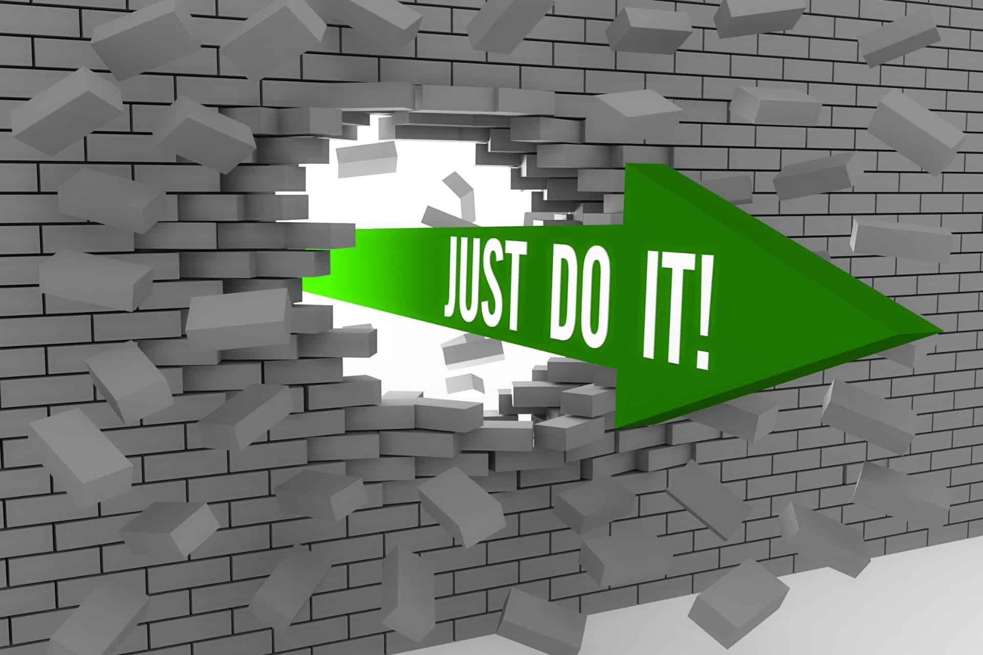Green arrow bursting through a gray brick wall with the text 'JUST DO IT!' in white letters.