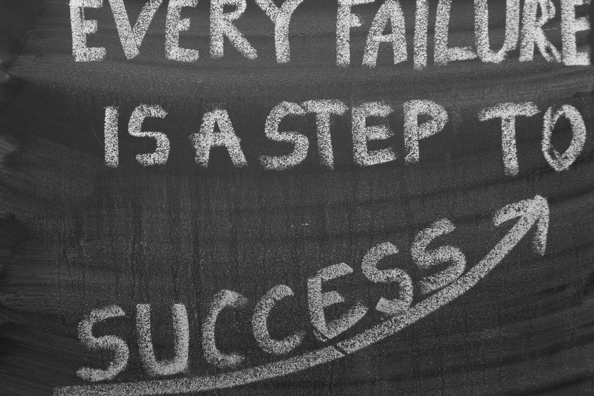 Chalkboard with the motivational phrase 'Every failure is a step to success' written in white chalk.