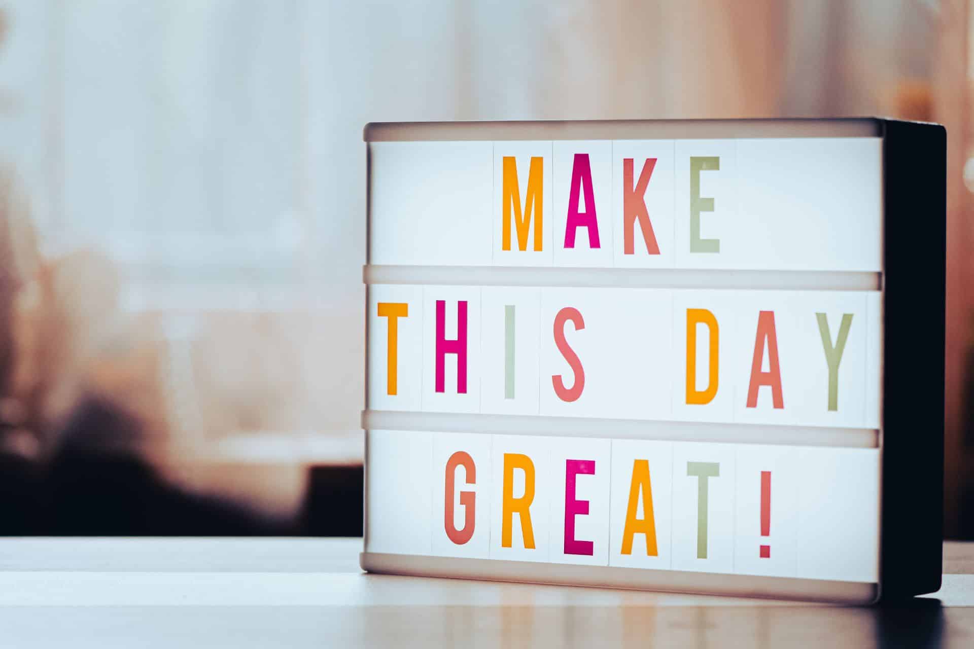 make this day great - The Sales Vault - The Sales Vault Lightbox sign with colorful letters spelling MAKE THIS DAY GREAT! on a desk in soft focus.