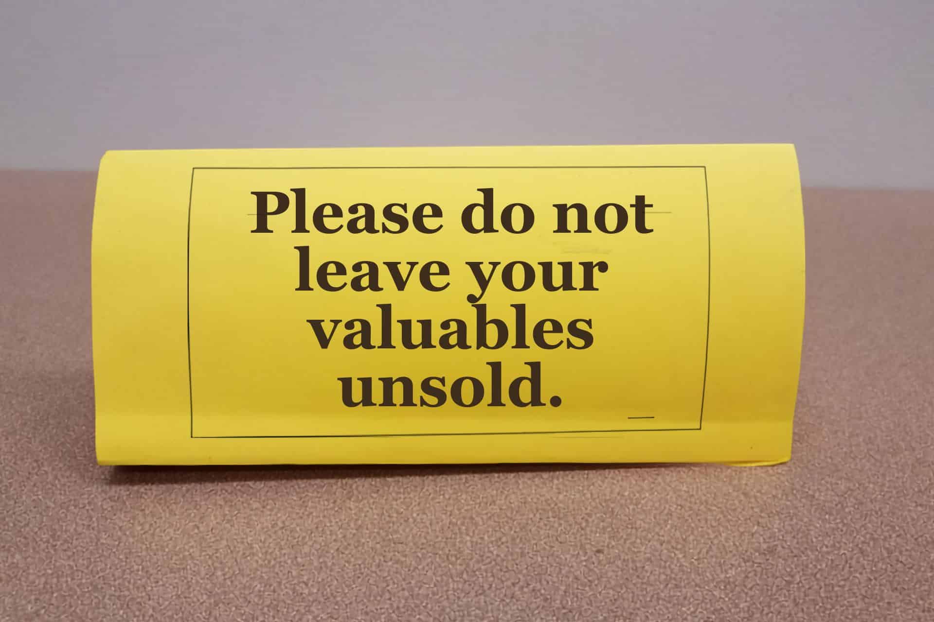 Bright yellow envelope on a brown carpet with the bold message: 'Please do not leave your valuables unsold.'